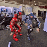 two motorcycle racers are standing next to each other in a room .