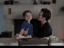 a man is holding a little boy in his arms in front of a fireplace