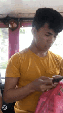 a man in a yellow shirt is using his phone