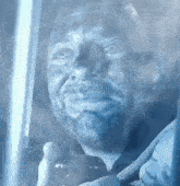 a man with a beard is holding a baby and looking out a window