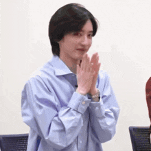 a young man wearing a blue shirt is clapping his hands .