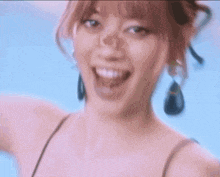 a woman wearing a pink top and black earrings is smiling with her mouth open .