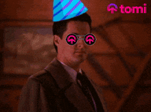 a man wearing a party hat and sunglasses is holding a gift and giving a thumbs up sign
