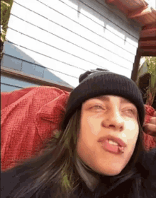 a woman with green hair is wearing a black beanie and making a face .