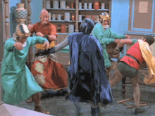 a group of men dressed in costumes including batman and robin are dancing in a room