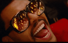 a man wearing sunglasses is laughing with his tongue out