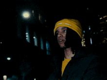 a person wearing a yellow beanie that says " i know i know " on it