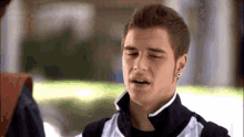 a young man with a piercing in his ear looks at the camera