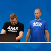 a man wearing a afas software shirt holds a sign that says computer says no