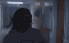 a man with dreadlocks is running down a hallway