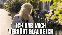 a woman is walking down a street with the words `` ich hab mich verhort glaube ich '' written above her .
