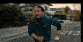 a man in a vest is running down a street with a football in his hand .