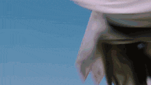 a person is standing in front of a blue sky with a white scarf around their neck