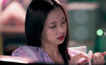 a woman in a purple shirt is sitting in a classroom looking down at something .