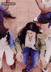 a group of people are sitting around a woman who is sitting on the ground .