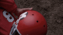 a football player wearing a red schutt helmet lays on the ground