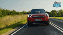 a red mini cooper is driving down a country road