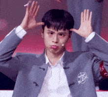 a man in a suit is making a funny face with his hands on his head .