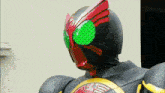a close up of a masked rider 's helmet with green eyes