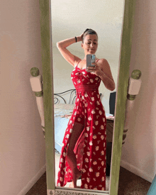 a woman in a red floral dress takes a selfie in front of a mirror