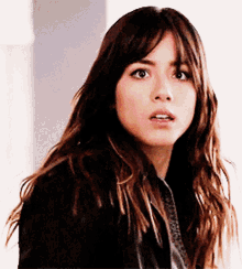 a woman with long hair is wearing a black jacket and tie