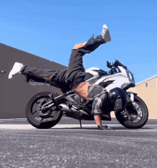 a man doing a handstand on a motorcycle that says kawasaki
