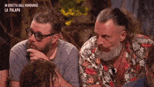 two men with beards are sitting next to each other in a room .