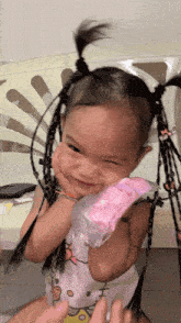 a little girl wearing a hello kitty shirt holds a pink glove