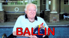 an elderly man is sitting in a pool with the word ballin written on his shirt