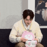 a man sitting on a couch holding a stuffed animal with a skull on it