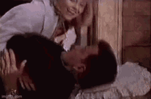 a man and a woman are kissing on a bed in a room .