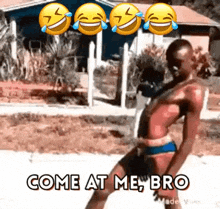 a man in a bikini is dancing in front of a house with smiley faces behind him .