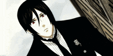 a man with black hair and red eyes is wearing a black suit and tie ..