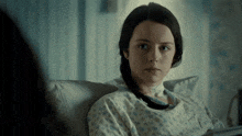 a woman in a hospital gown is sitting in a hospital bed