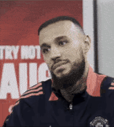 a man with a beard wearing a manchester united jacket