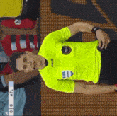 a referee wearing a yellow shirt that says fifa