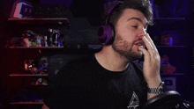 a man with a beard wearing purple headphones and a black shirt