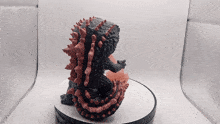 a statue of a monster with red spikes is sitting on a table