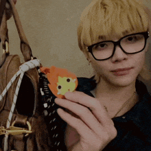 a person wearing glasses is holding a stuffed animal in their hands