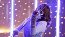 a woman playing a violin in front of a purple background