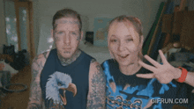 a man and a woman are posing for a picture with gifrun.com written on the bottom right