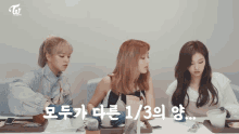 three girls sitting at a table with a twice logo on the top