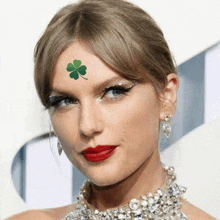 a close up of a woman 's face with a green four leaf clover on her forehead .