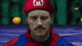 a man with a mustache and a red hat with a letter m on it