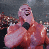 a wrestler holds his hand to his mouth in front of a sign that says wwe