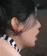 a close up of a woman 's ear with red heart shaped earrings