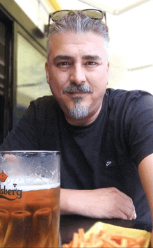 a man sits at a table with a glass of beer that says carlsberg