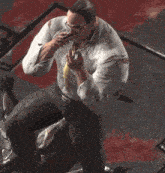 a man wearing glasses and a tie is sitting on the floor