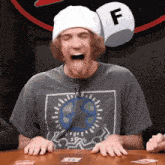 a man wearing a beanie and a shirt with the letter f on it is laughing