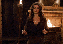 a woman standing in front of a fireplace holding a torch